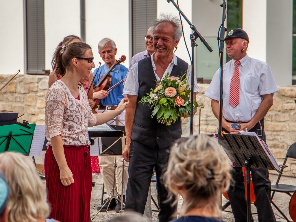 Dirigent Dietrich Schöller-Manno bekommt als Dankeschön einen Blumenstrauß überreicht