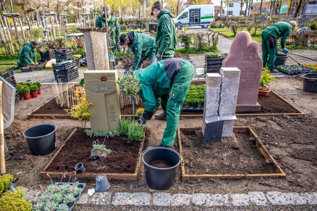 Zu sehen sind Gärtner bei der Arbeit an den individuell gestalteten Grabanlagen auf dem städtischen Friedhof
