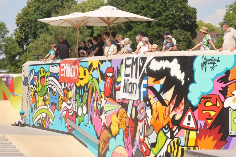 Zuschauer stehen oberhalb der Graffitiwand im Skatepark