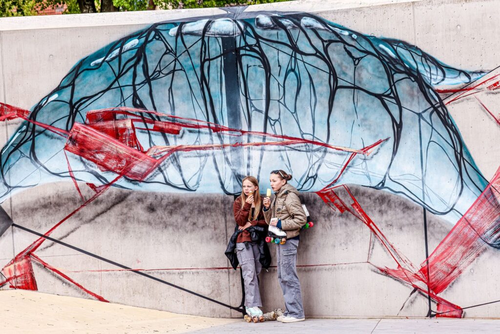 Zwei Mädchen stehen mit einem Eis in der Hand vor dem Bubble-Graffiti von Janosch Müller